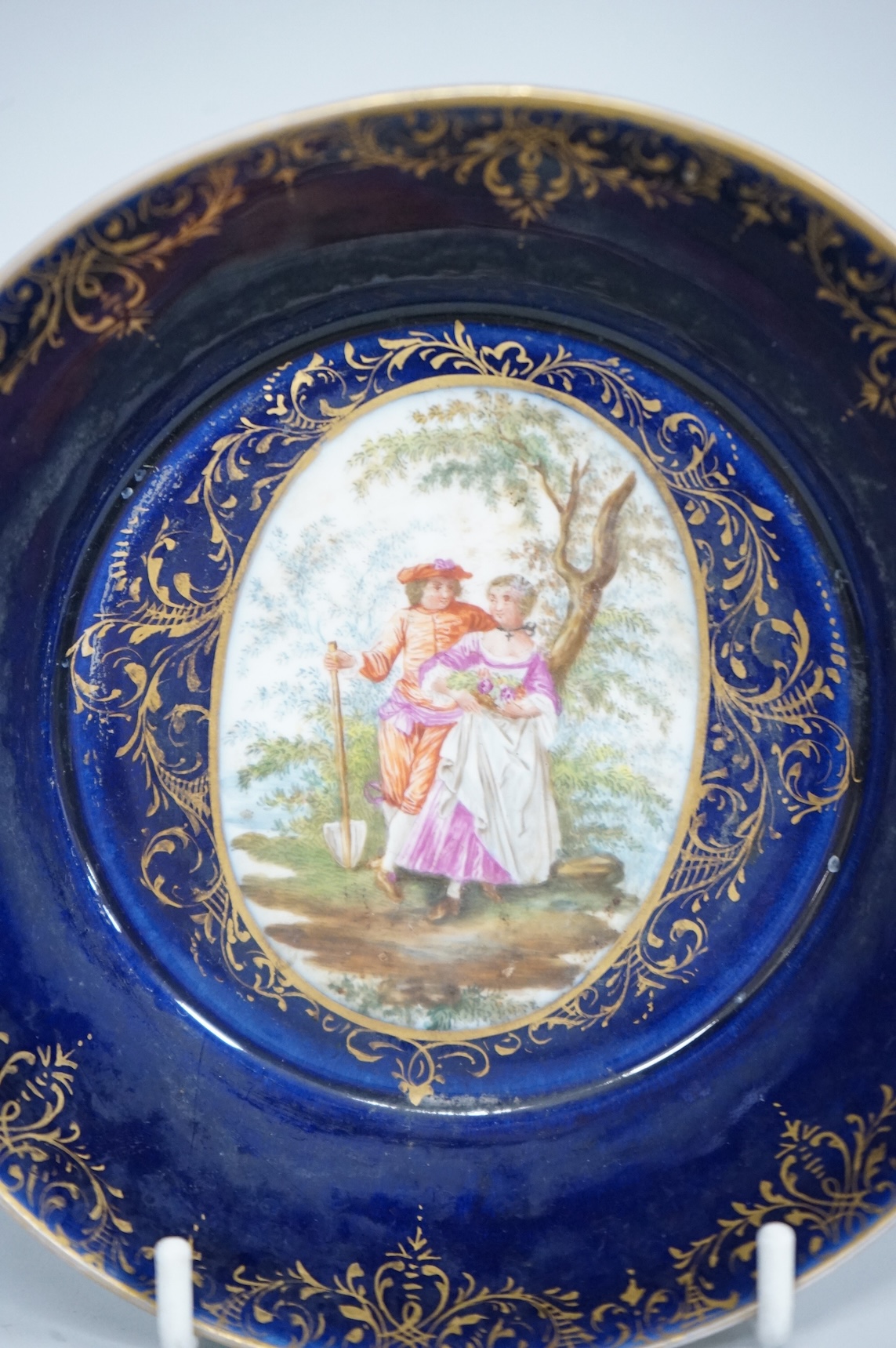 A 19th century Vienna saucer, hand painted with two figures beneath a tree, 15cm in diameter
